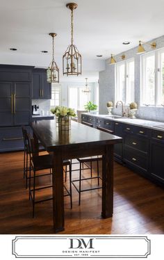 a large kitchen with wooden floors and black cabinetry, along with an island in the middle