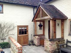 a small white brick house with a wooden door and bench next to the front entrance