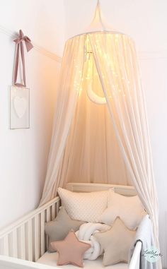 a baby crib with a canopy over it's head and pillows on the floor