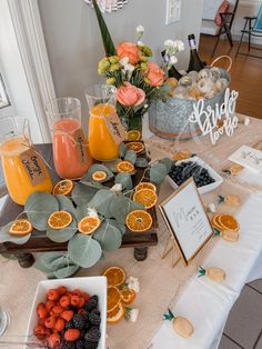 a table topped with oranges, berries and other fruits on top of a white table cloth