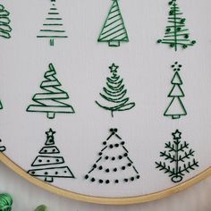 a close up of a cross stitch pattern on a white cloth with green thread and various christmas trees