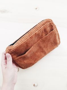 a person holding an empty brown corded purse