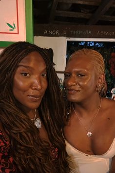 two women standing next to each other in front of a green wall