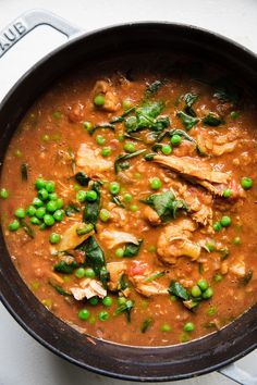 a pan filled with meat and peas on top of a table