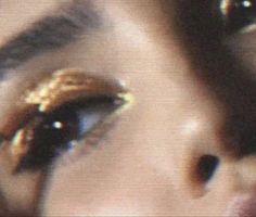 a woman's eye with gold glitter on it and her reflection in the lens