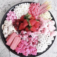 a bowl filled with marshmallows, strawberries, and other candy toppings