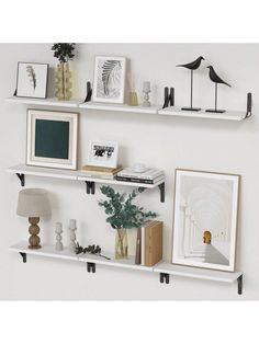 three white shelves with pictures on them and some plants in vases next to each other