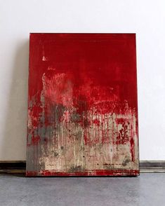 a red painting sitting on top of a floor next to a white wall