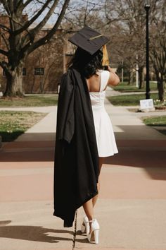 a woman in a graduation cap and gown walks down the street with her hand on her hip