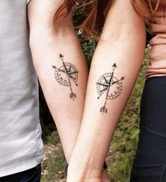 two people with tattoos on their arms holding hands