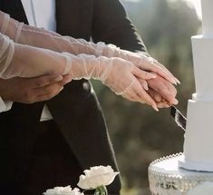 the bride and groom are cutting their wedding cake with white frosted icing on it