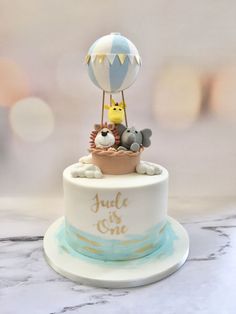 a birthday cake with an air balloon and animals on top