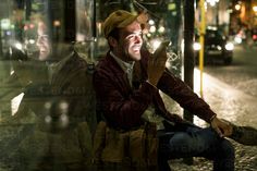 a man sitting on a bench looking at his cell phone in the street by himself