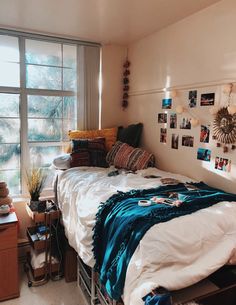 an unmade bed sitting in a bedroom next to a window with pictures on the wall