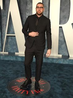 a man in a suit and tie standing on a blue carpet