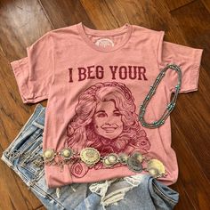 I Beg Your Parton Tee, Dolly Parton T-Shirt. You don't have this tee yet? I beg your...?! Our best-selling tee of all time, featuring the one and only queen Dolly. It is on a heather orchid tee that is lightweight, stretchy, and a true-to-size unisex fit and the design is a screen print, so won't fade or peel after washing. 52% cotton 48% polyester Western Boutique Clothing, Dolly Parton T Shirt, Western Tee, Western Boutique, Western Graphic Tees, Western Women, Rose Boutique, The One And Only, Dolly Parton