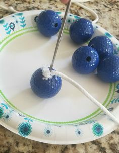 a plate with four blue golf balls on it and a pair of scissors in the middle