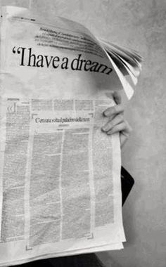 a person holding up a newspaper with the words have a dream written on it in black and white