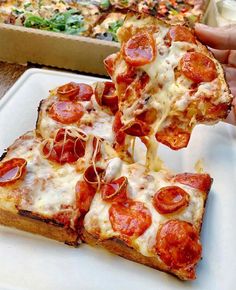 two slices of pepperoni pizza being lifted from a pan by someone's hand