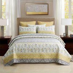 a bed with yellow and white bedspread in a bedroom next to two nightstands