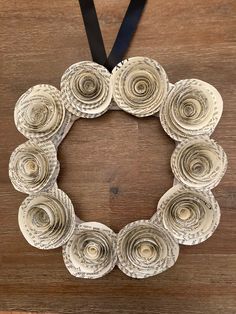 an ornament made out of rolled up books is hanging on a wooden table