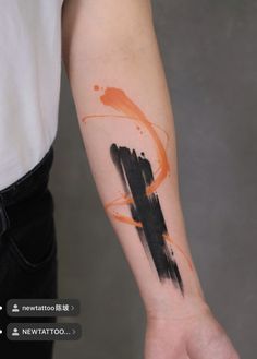 an orange and black ink splattered on the arm with a cross tattoo design