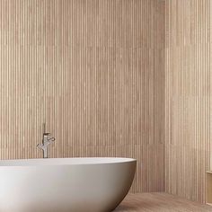 a white bath tub sitting on top of a wooden floor next to a wall mounted shower head