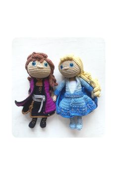 two crocheted dolls sitting next to each other on top of a white surface