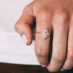 a person's hand with a ring on top of their finger and the other hand holding