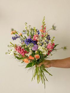 a person holding a bouquet of flowers in their left hand and the other hand is reaching for it