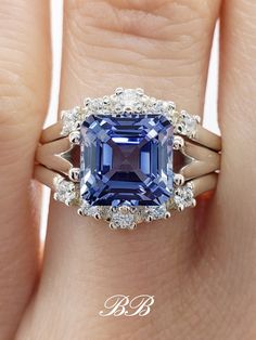 a woman's hand holding an engagement ring with a blue sapphire and diamonds on it