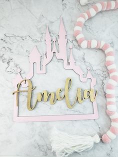 a pink and gold name sign with a castle in the background on a marble surface