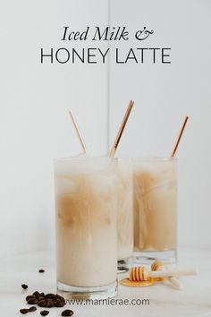 two glasses filled with iced milk and honey latte on top of a white table