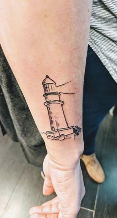 a small lighthouse tattoo on the wrist