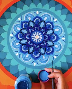 someone is painting a blue and orange flower on the wall with acrylic paint