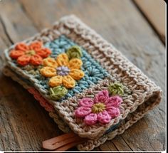 a crocheted book with flowers on it sitting on top of a wooden table