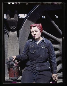 a woman in overalls and a red bandana is holding a fire hydrant