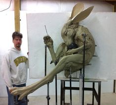 a man standing next to a sculpture of a rabbit