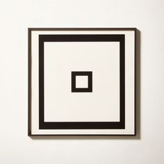 a black and white square is on the wall in front of a white frame with a small square at the center