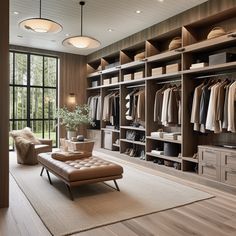 a large walk - in closet with lots of clothes on shelves, and a footstool