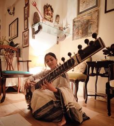 a woman sitting on the floor playing an instrument