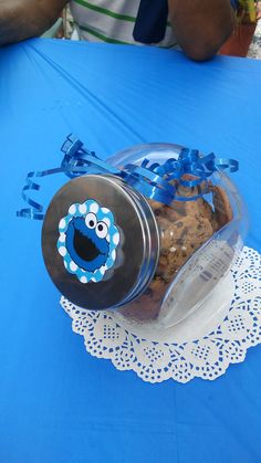 cookie jar with cookie cookies in it sitting on a blue tablecloth at an outdoor event