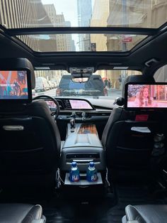 the back seats of a car with two televisions in it's center console