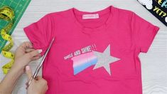 someone using scissors to cut out a t - shirt with pink and silver stars on it