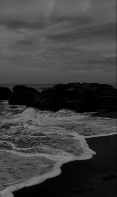 the ocean is dark and stormy with waves coming in to shore on an overcast day