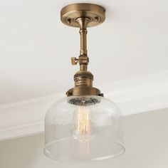 a light fixture with a clear glass dome on the top and an old - fashioned brass finish