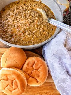 a bowl of soup next to buns on a cutting board