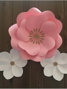 paper flowers are arranged on a wooden surface, with one large pink flower in the center