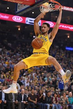 a basketball player jumping up into the air with a ball in his hand and people watching