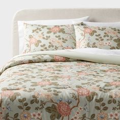 a bed with floral comforter and pillows